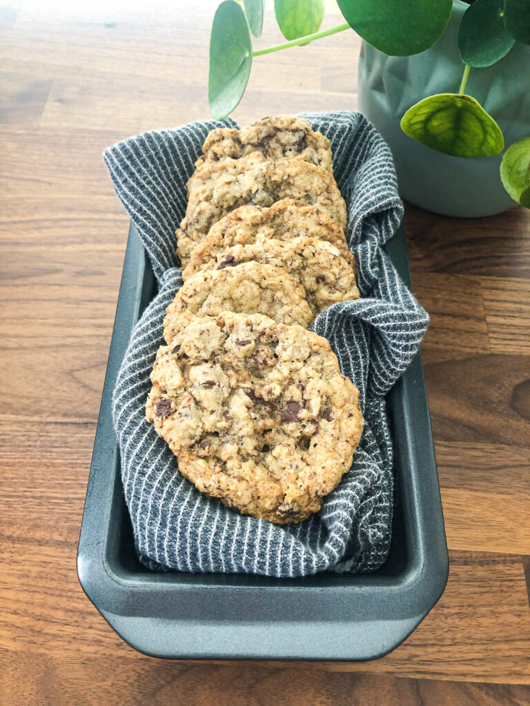 Gluten free oatmeal chocolate cookies placed in a tea towel inside a loaf pan for decoration.