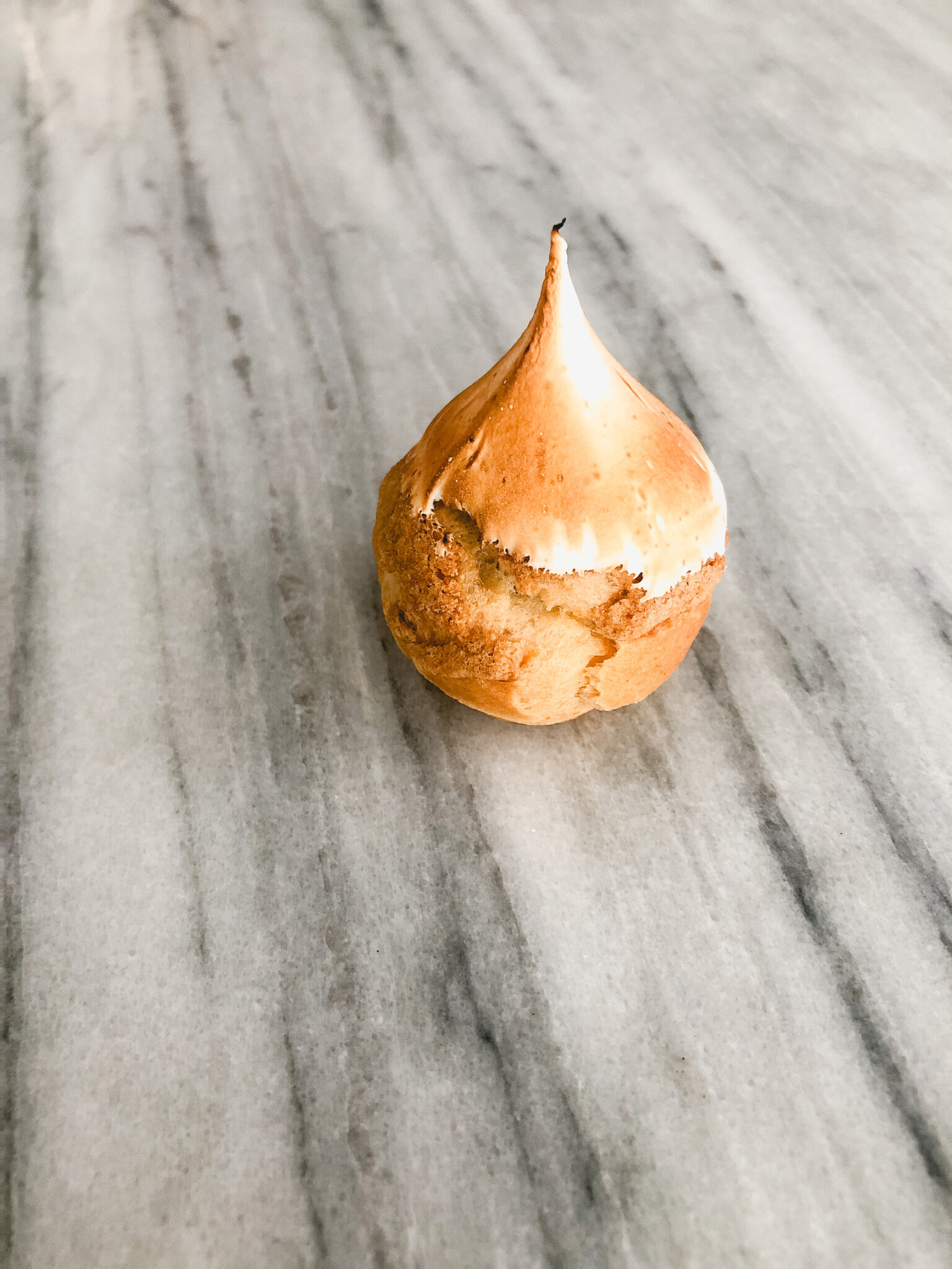 Gluten free lemon meringue cream puff on a marble table