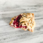 Single gluten free white chocolate raspberry scone on a marble table