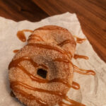 Gluten free cinnamon sugar donuts drizzled with salted caramel laying on parchment paper
