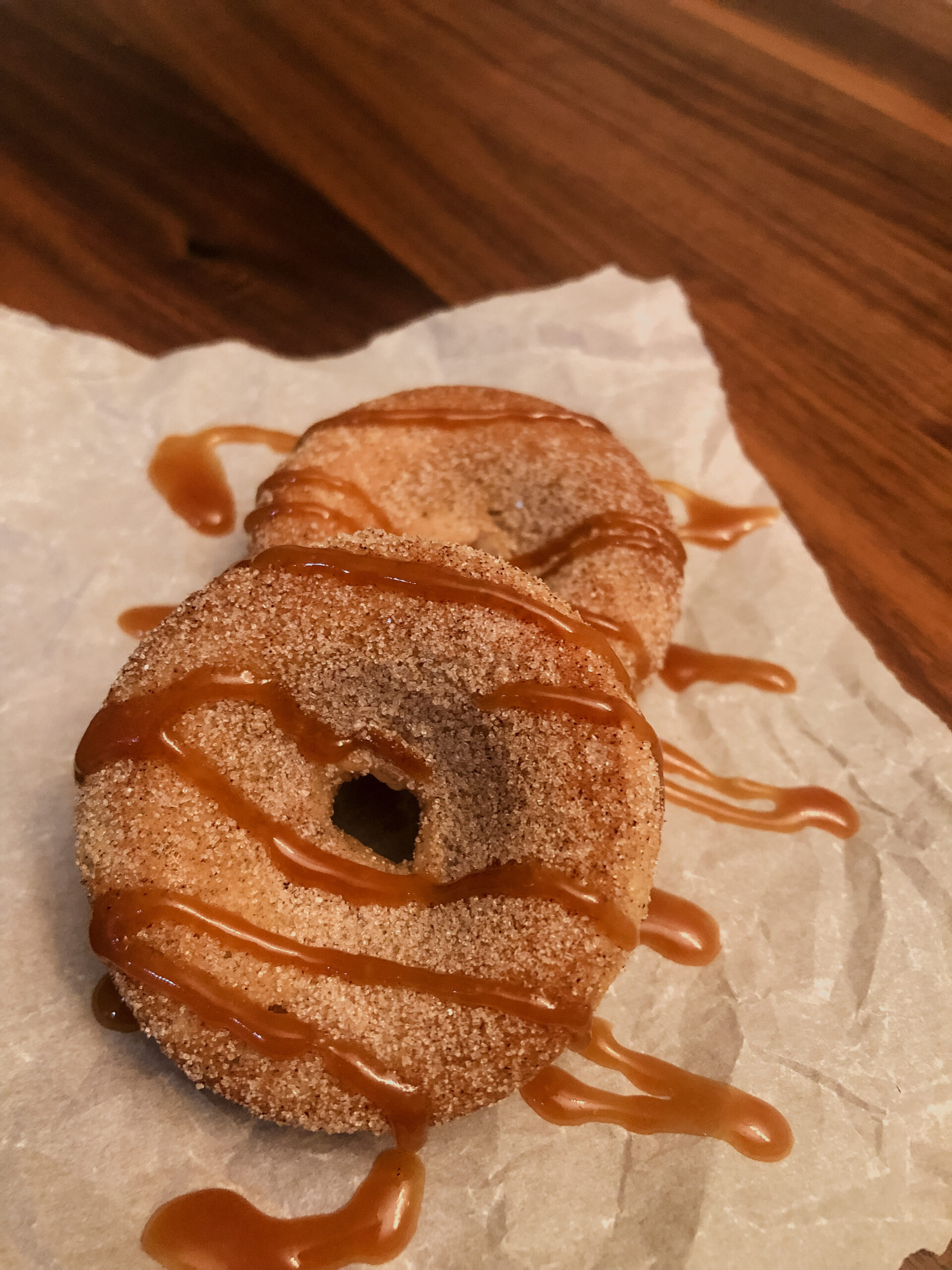 Gluten free cinnamon sugar donuts / doughnuts drizzled with salted caramel laying on parchment paper