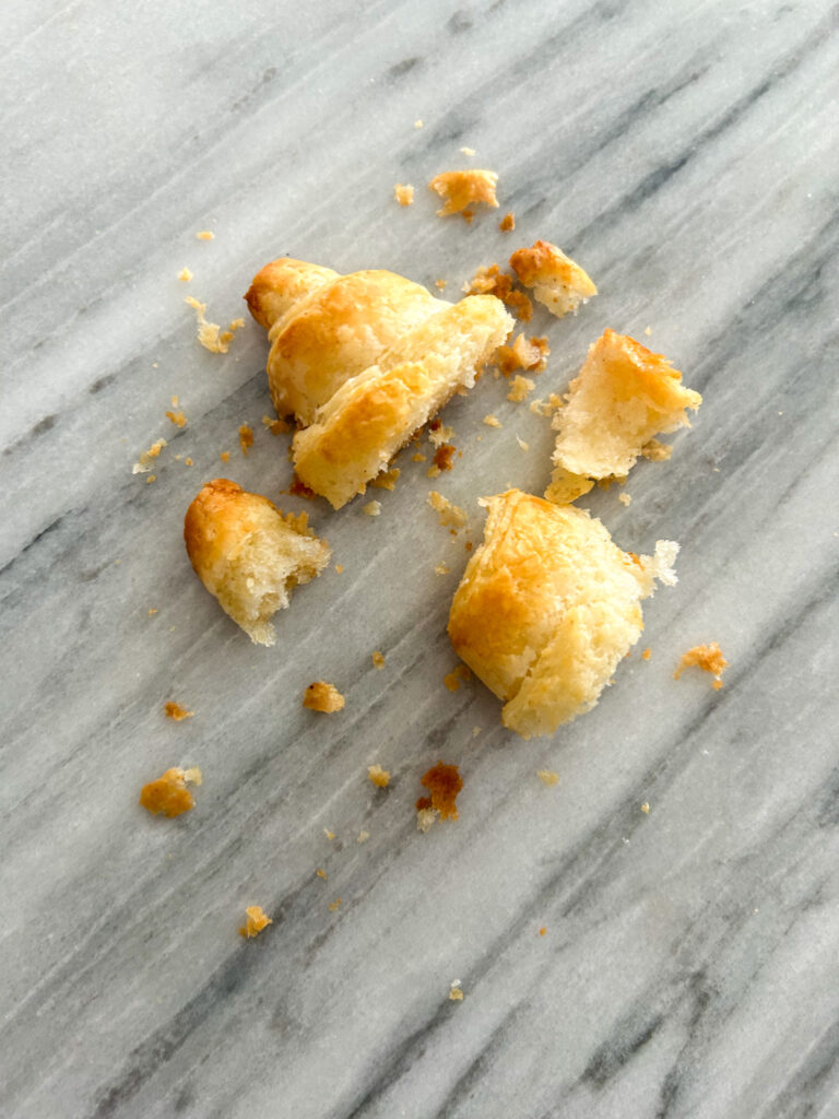 Flaky and pulled apart gluten free croissant on a table