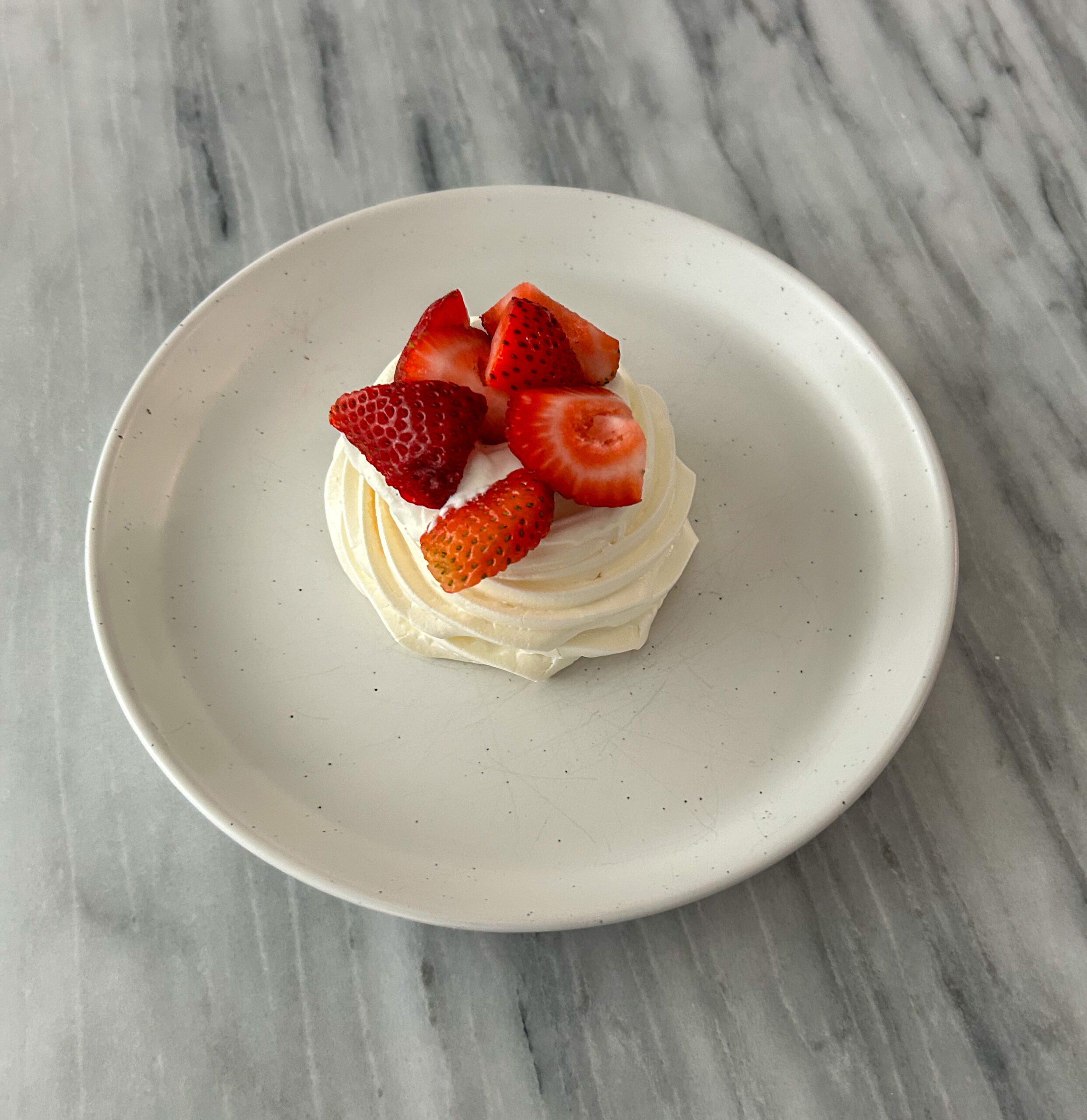 Mini Pavlova covered in strawberries and whipped cream